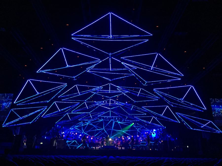Geometric lighting rig glowing blue over an arena stage