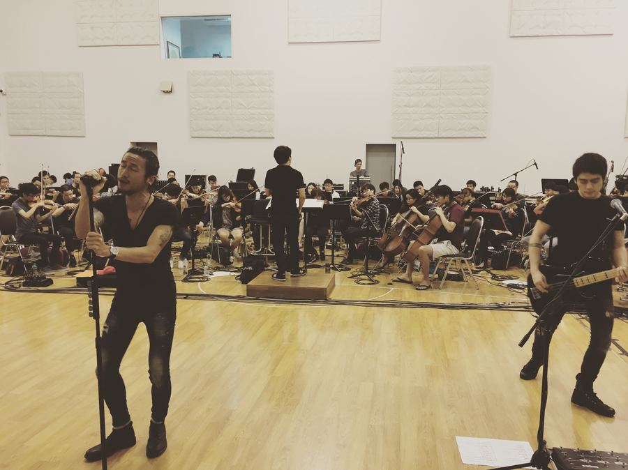 Singer and bassist rehearsing in front of an orchestra