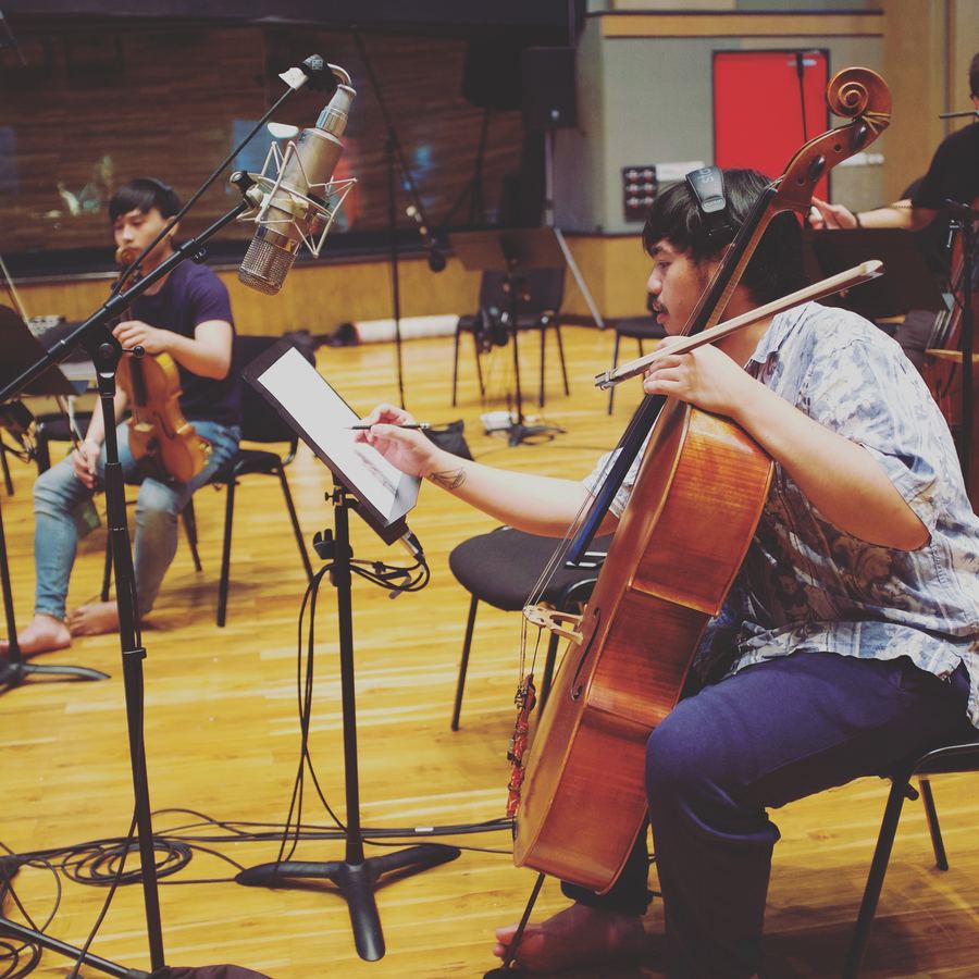 Cellist reading from a tablet beside a close microphone
