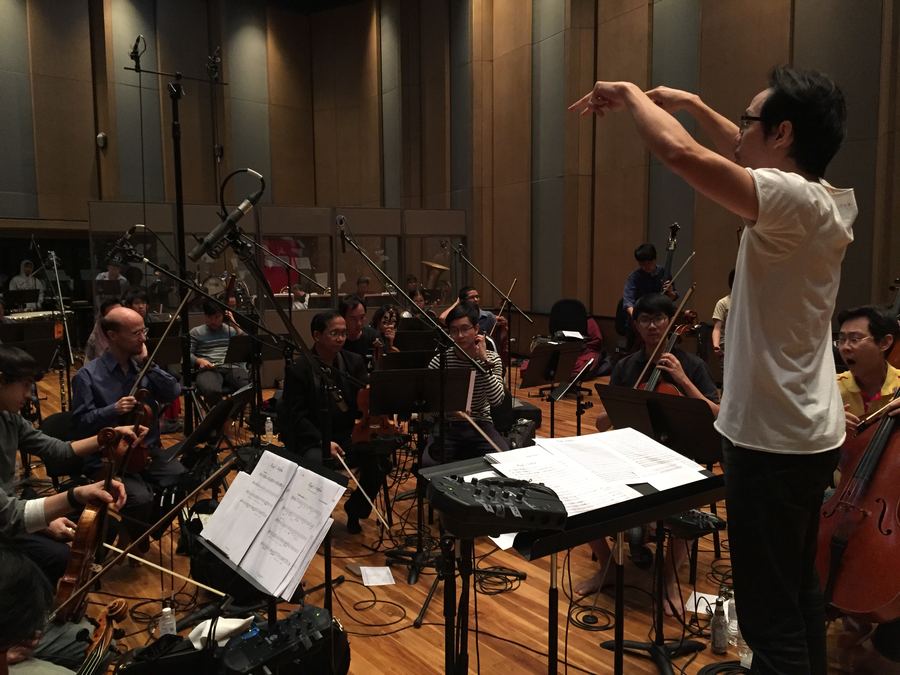 Conductor leading an orchestra in the live room
