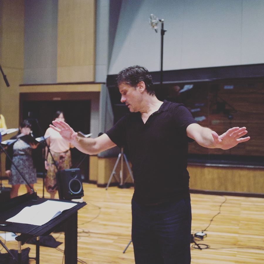 Conductor with arms outstretched in front of an ensemble