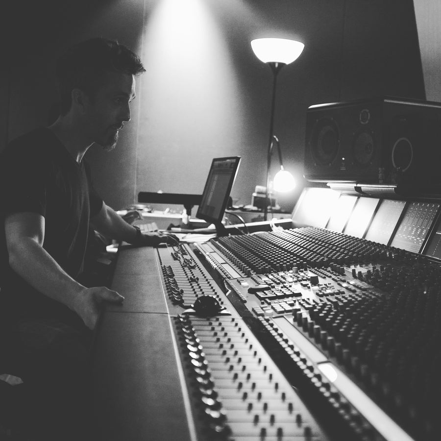 Engineer at a large-format console in a dim control room