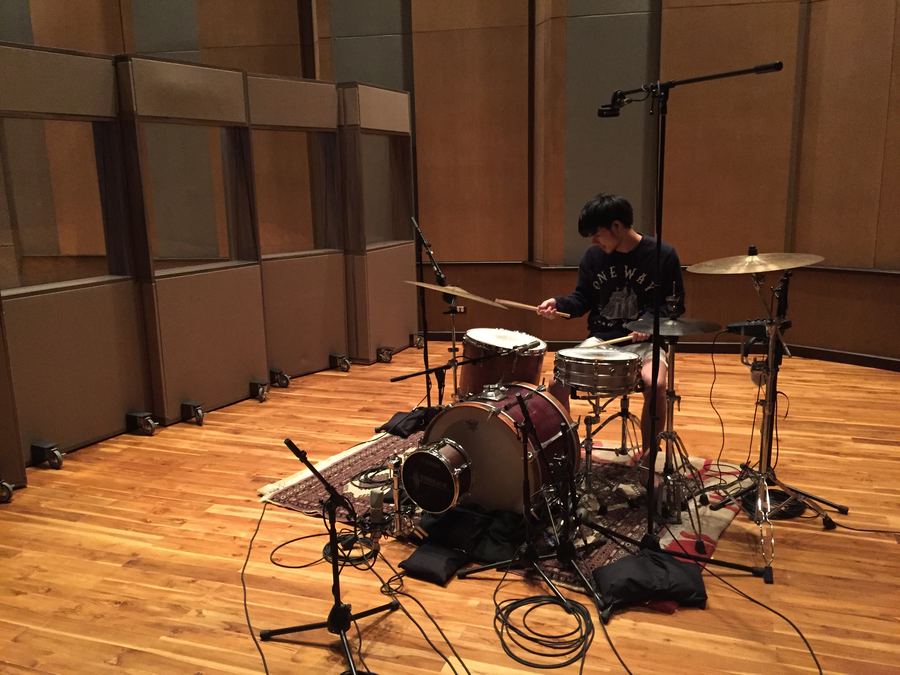 Drummer at a kit in a wood-panelled live room