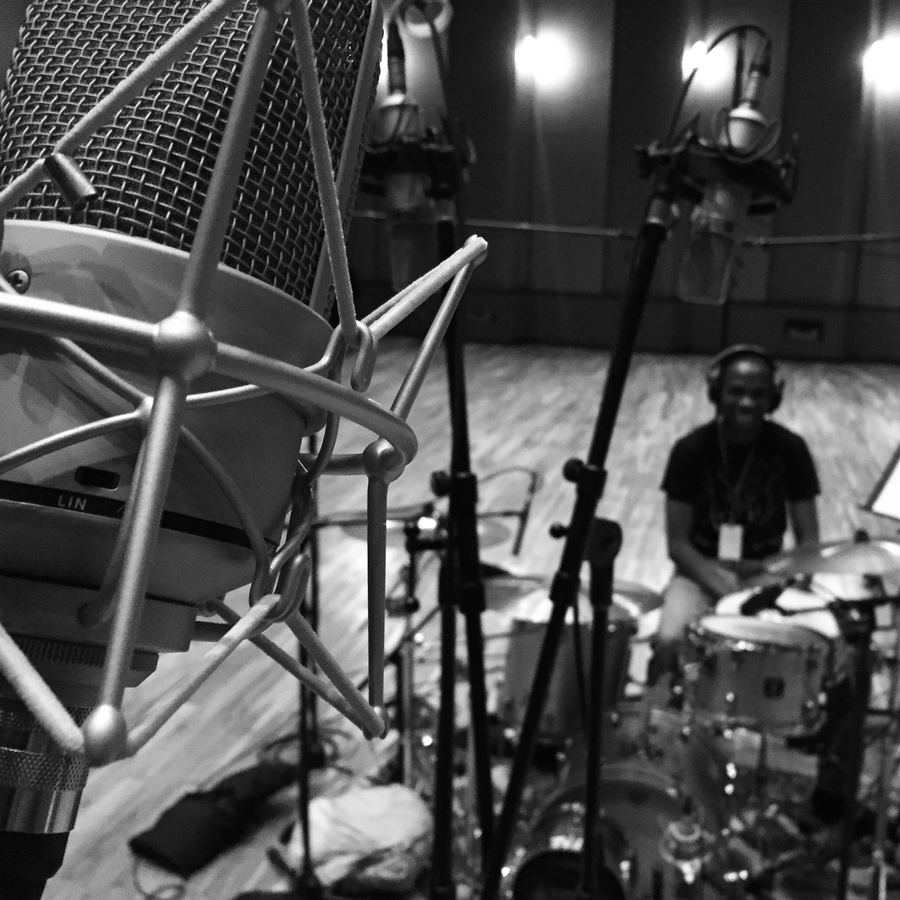 Drummer seen through a forest of microphone stands