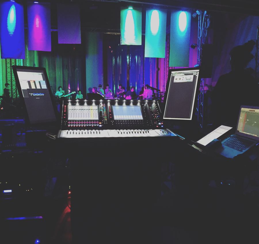 Front-of-house desk with screens, band lit on stage