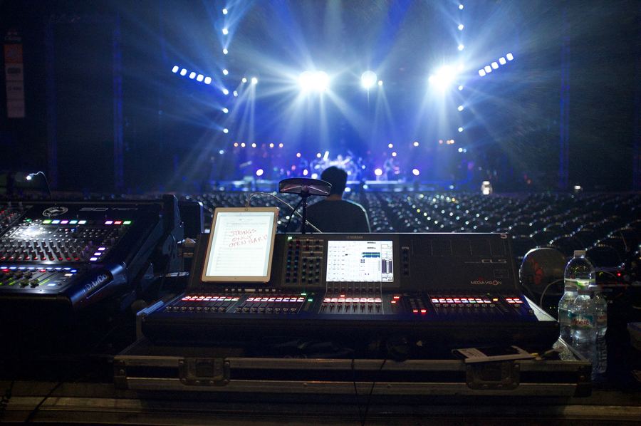 Front-of-house mixing desk facing a lit arena stage