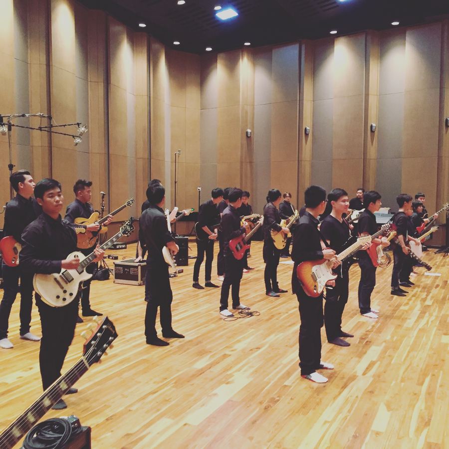 Rows of guitarists playing together in the live room