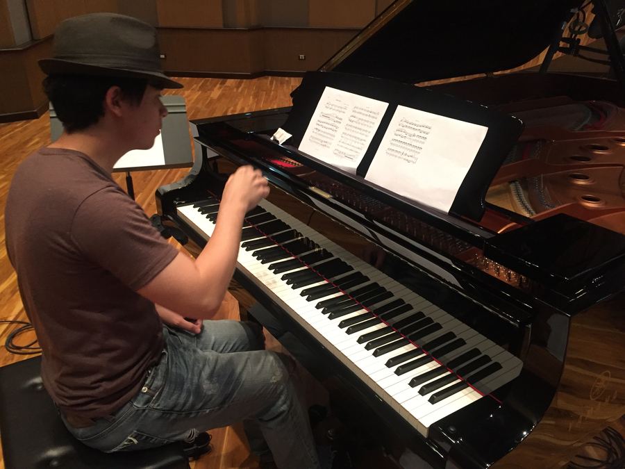 Pianist in a hat reading a score at the grand piano