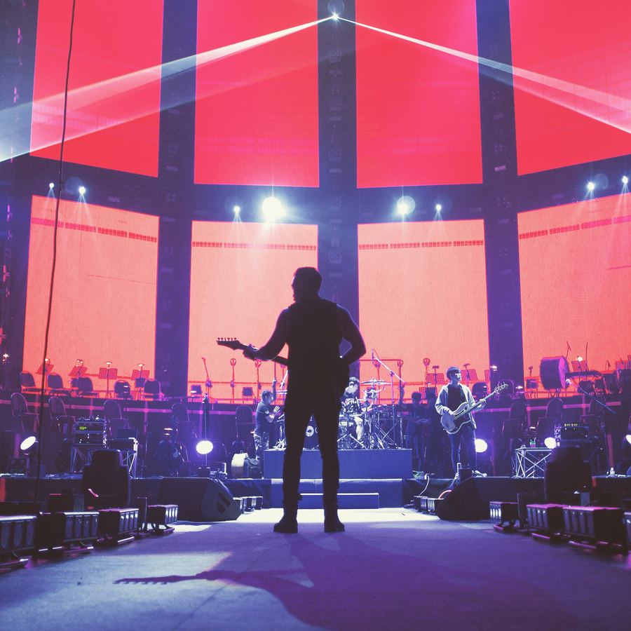Guitarist silhouetted against a red stage backdrop