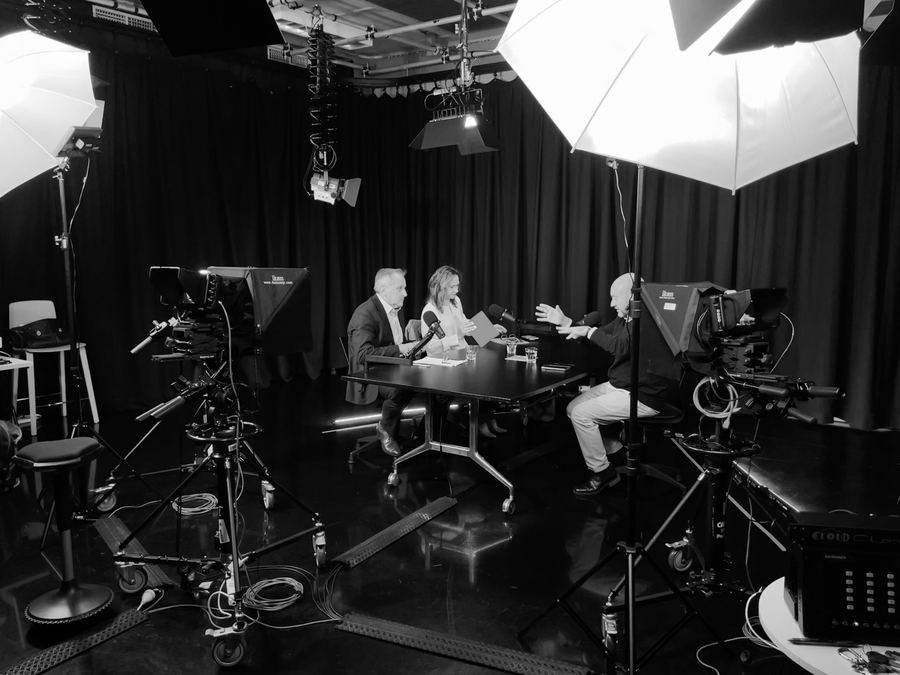 Panel discussion at a table, cameras on pedestals in the foreground