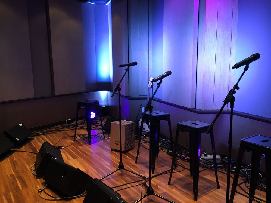 Microphones and stools lit blue, ready for a vocal group