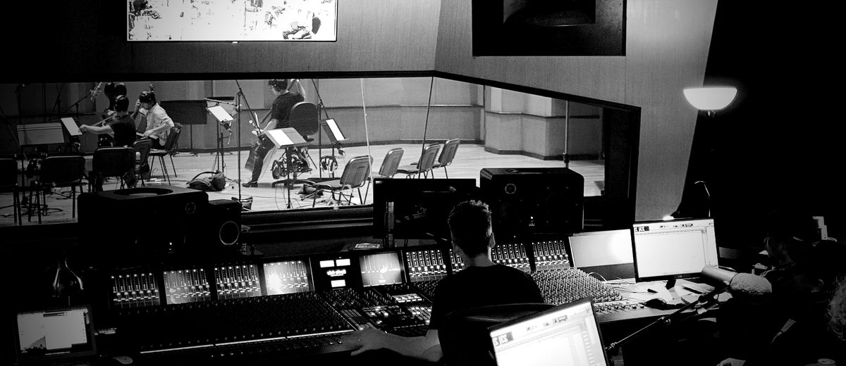 An orchestral session seen from the control room, engineer at the console